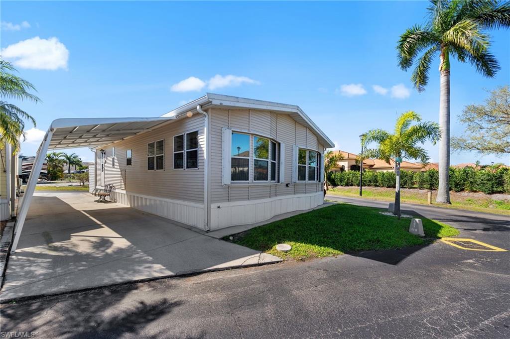 View of front of property featuring an attached carport, concrete driveway, and a front yard