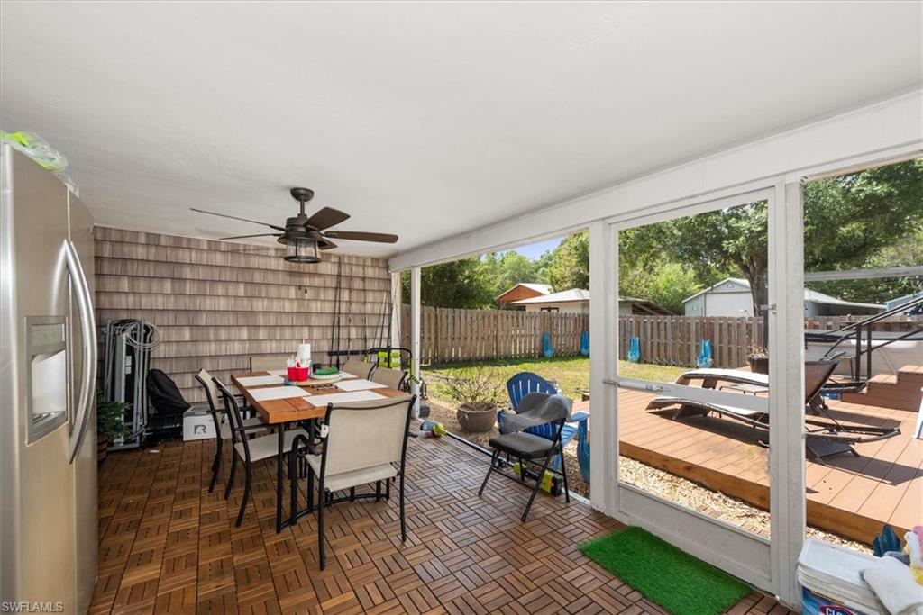 Sunroom / solarium with outdoor dining area, a ceiling fan, a patio area, and a wooden deck