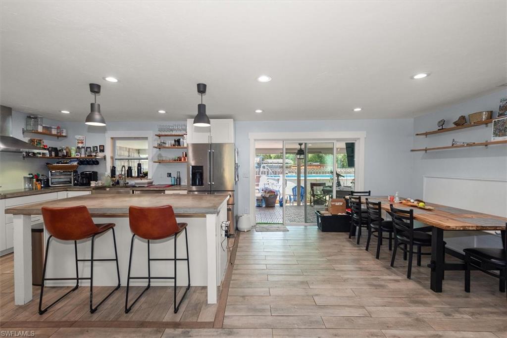 Kitchen featuring open shelves, white cabinetry, a center island, a breakfast bar, and pendant lighting