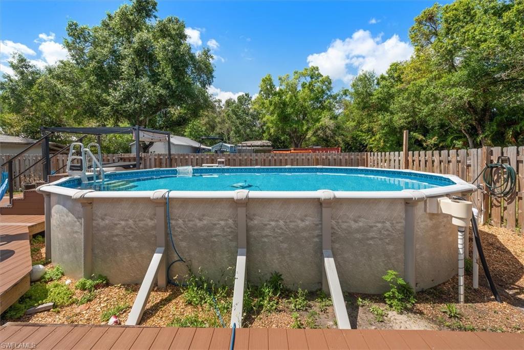 View of pool with a fenced backyard, a wooden deck, and view of wooded area