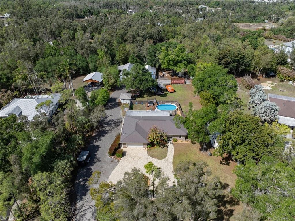 View from above of property featuring a heavily wooded area and a pool