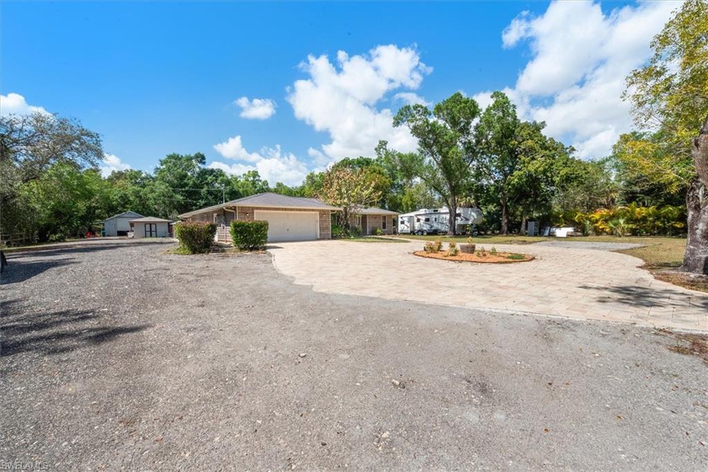 Single story home featuring curved driveway and view of scattered trees