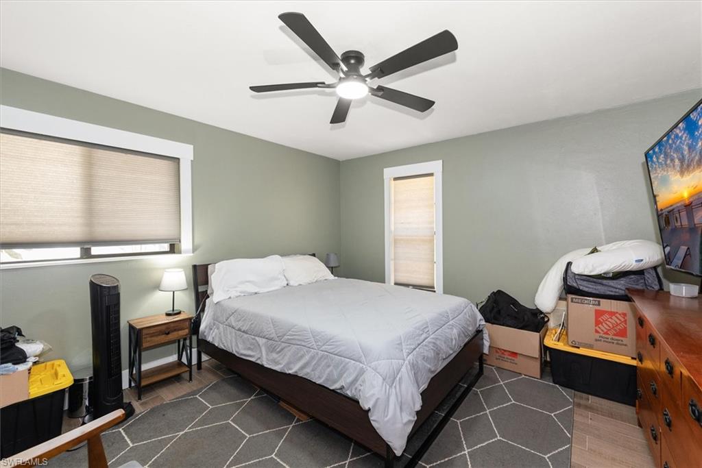 Bedroom with wood finished floors, ceiling fan, and multiple windows