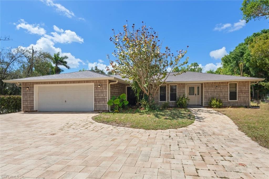 Ranch-style house featuring decorative driveway, a garage, and a front yard