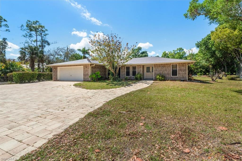 Ranch-style house with an attached garage, decorative driveway, and a front yard