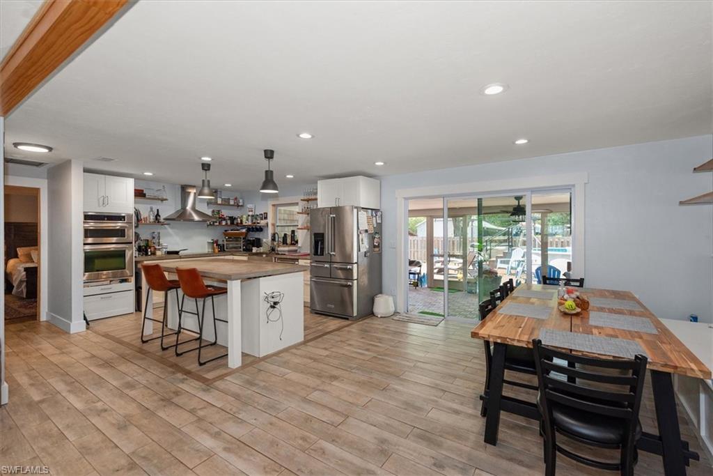 Kitchen featuring white cabinets, open shelves, stainless steel appliances, wood counters, and a center island