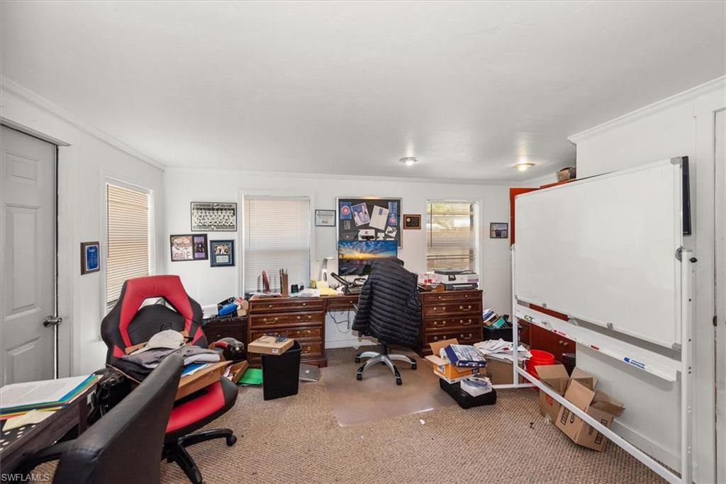 Office area with crown molding and light carpet