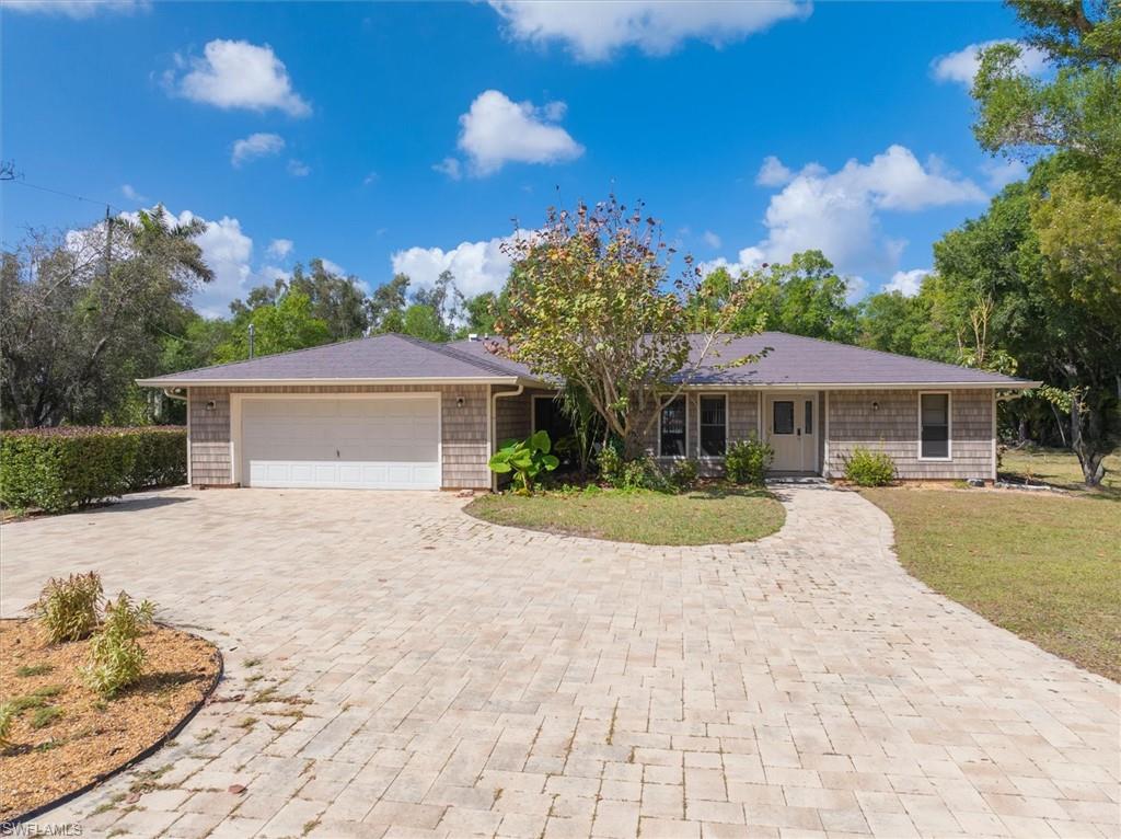 Ranch-style house with a garage, decorative driveway, and a front yard