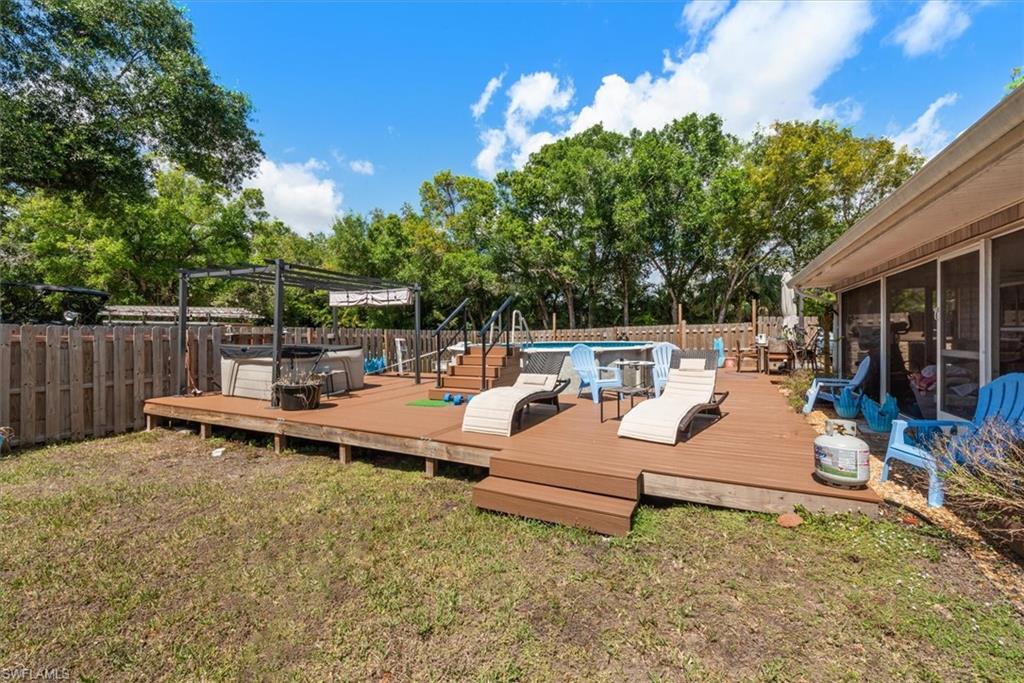 Wooden deck with a sunroom, a fenced backyard, view of wooded area, and a jacuzzi