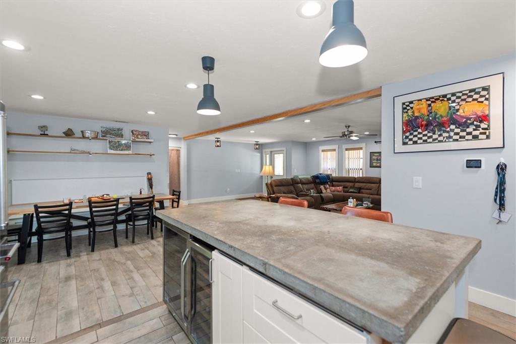 Kitchen with white cabinetry, open floor plan, hanging light fixtures, beverage cooler, and light wood finished floors