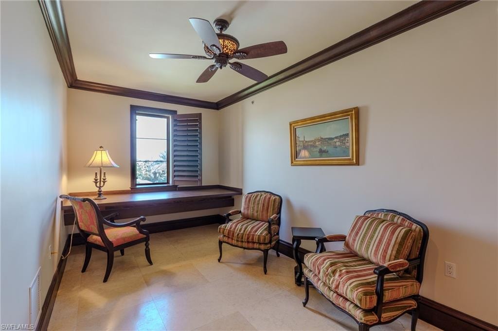 Living area with ornamental molding, a ceiling fan, a desk, and light floors