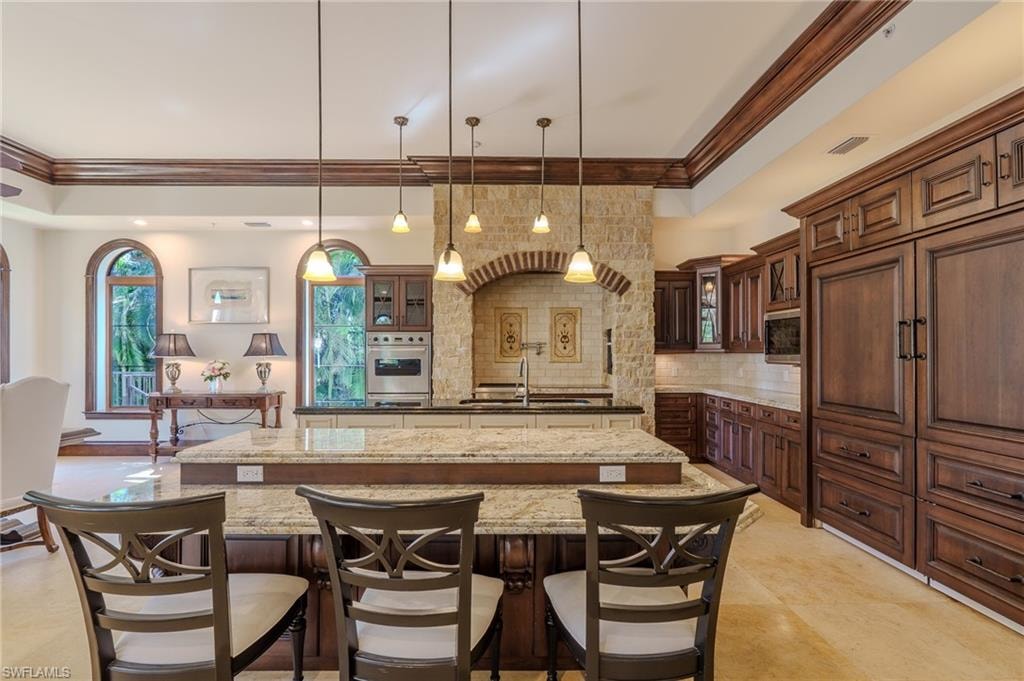 Kitchen featuring glass insert cabinets, dark stone countertops, crown molding, stainless steel appliances, and a tray ceiling