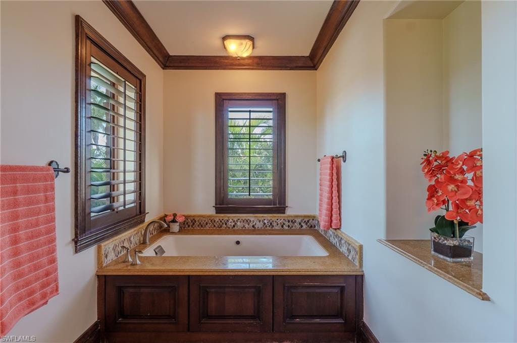 Bathroom with a garden tub and crown molding