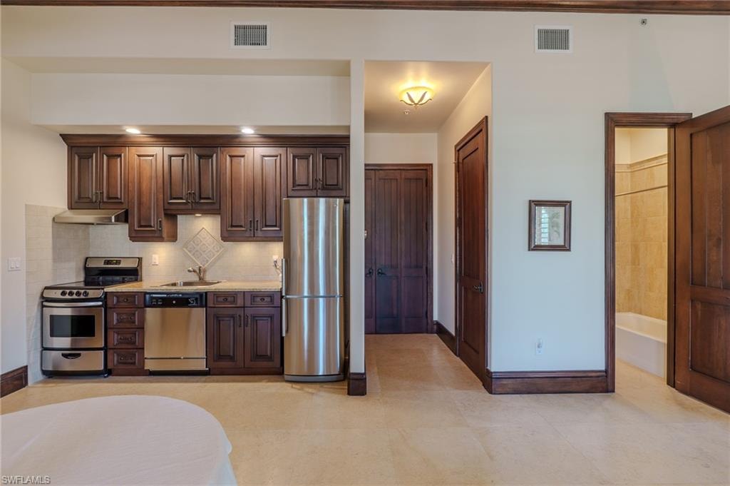 Kitchen featuring dark wood finish cabinets, stainless steel appliances, and tasteful backsplash
