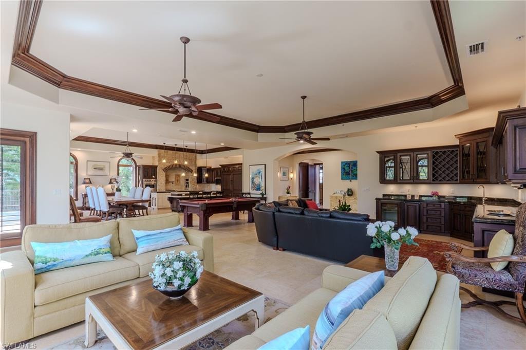 Living area with arched walkways, ornamental molding, billiards, a tray ceiling, and ceiling fan