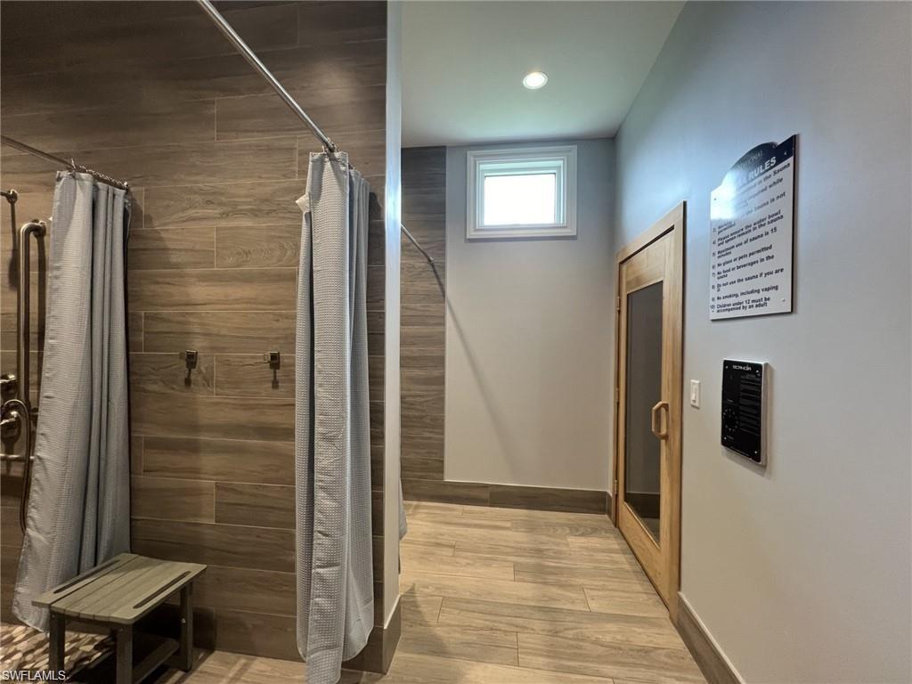 Locker room featuring a shower stall, sauna, light wood finished floors, and recessed lighting