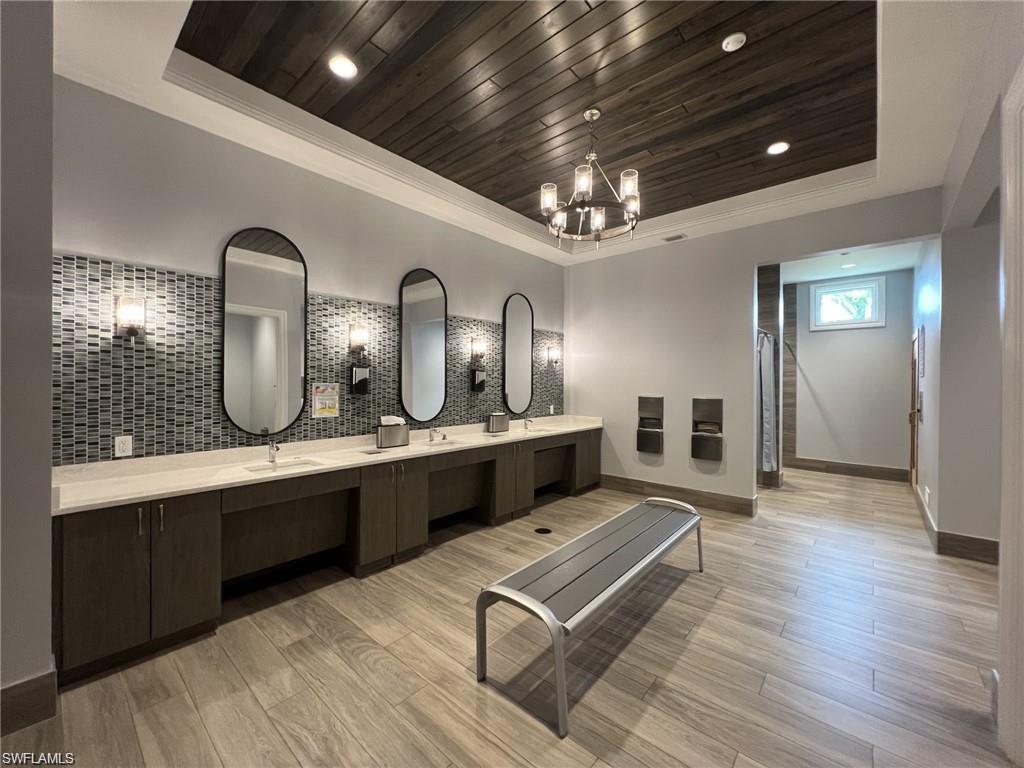 Community Bathroom/Locker room featuring double vanity, a wooden tray ceiling, and hanging lights