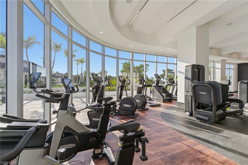 Workout area with floor to ceiling windows, a high ceiling, and recessed lighting