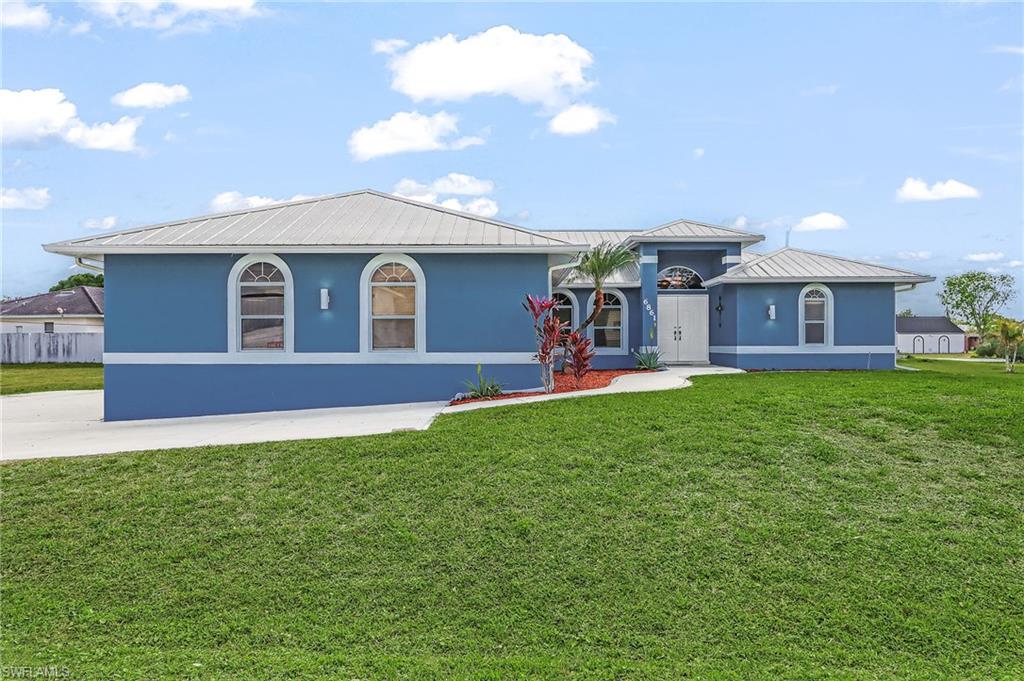 View of front of property with a metal roof, stucco siding, and a front lawn