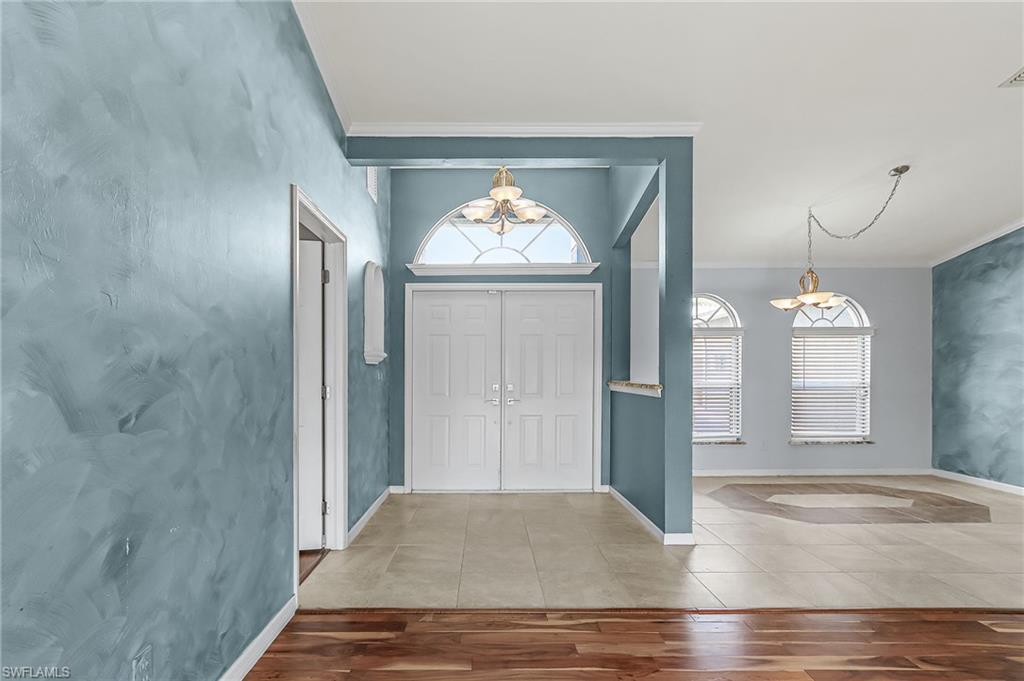 Foyer with crown molding, tile patterned floors, and hanging lights