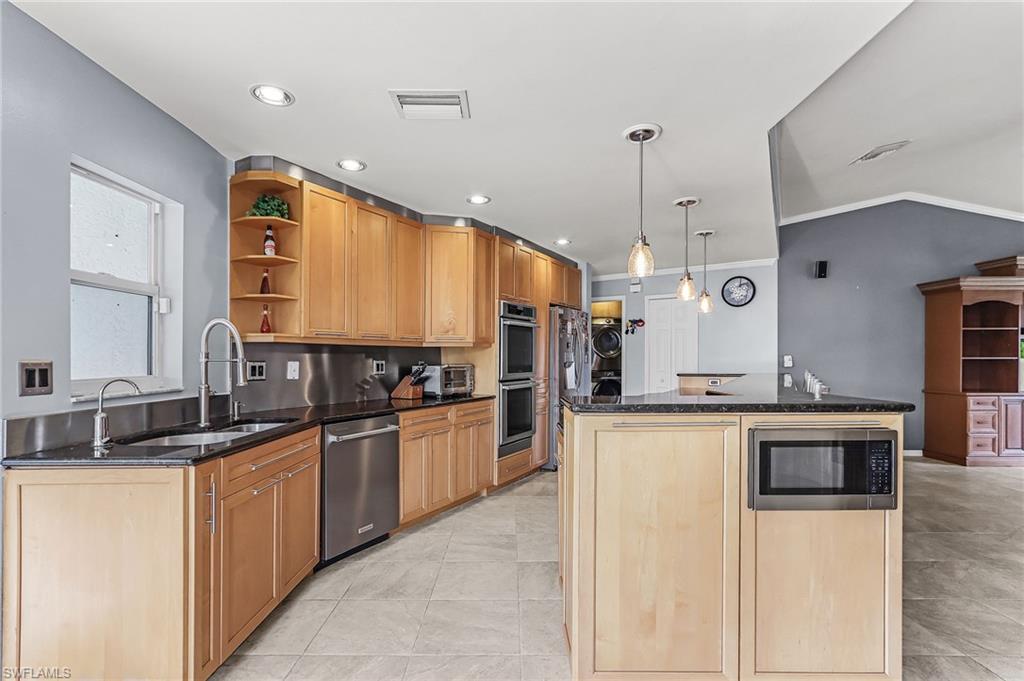 Kitchen featuring open shelves, dark stone counters, a kitchen island, stainless steel appliances, and crown molding