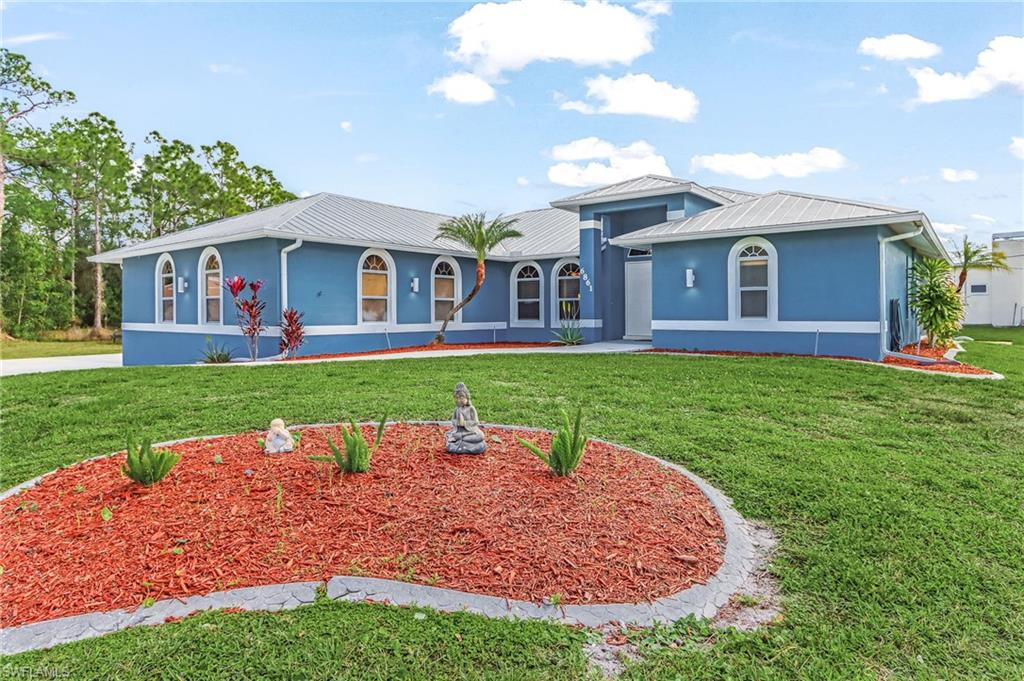 View of front of home with stucco siding, a front lawn, and a metal roof