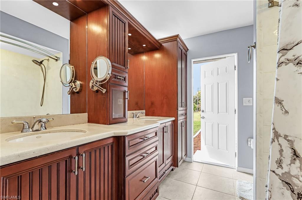 Bathroom with double vanity, light tile patterned floors, and a shower