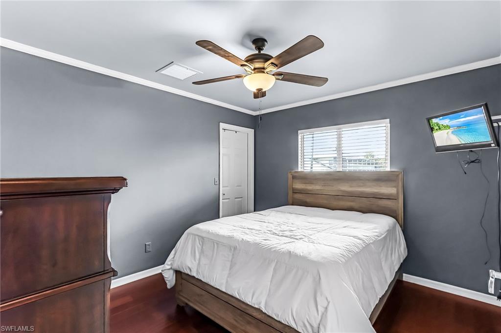 Bedroom featuring ornamental molding, dark wood finished floors, and ceiling fan