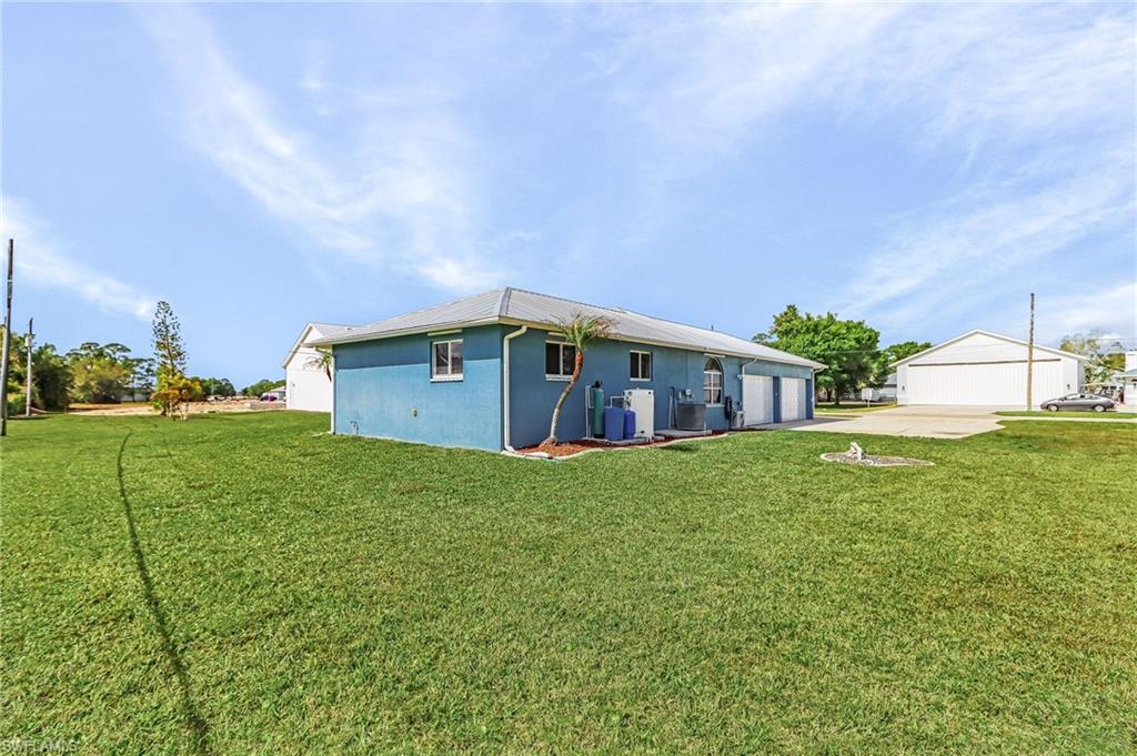 Rear view of property with a yard, a garage, stucco siding, and concrete driveway