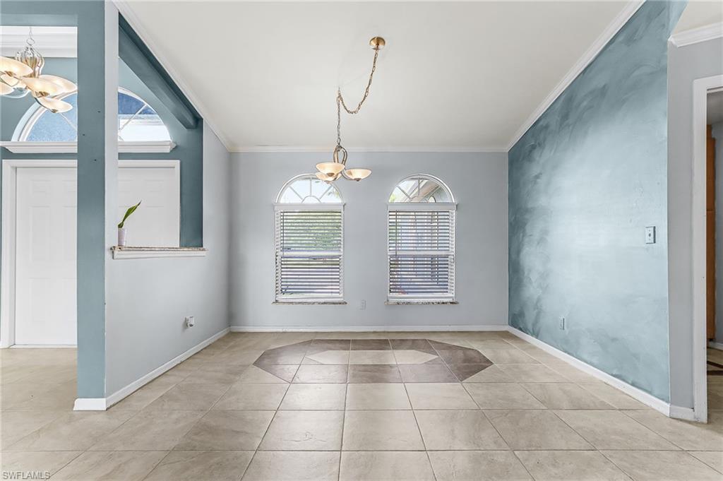 Unfurnished dining area featuring hanging lights, crown molding, and light tile patterned flooring
