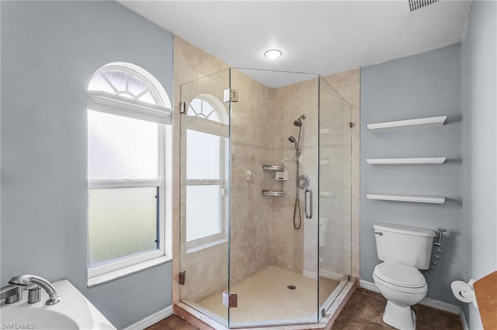 Full bath featuring a shower stall, vanity, and dark tile patterned flooring