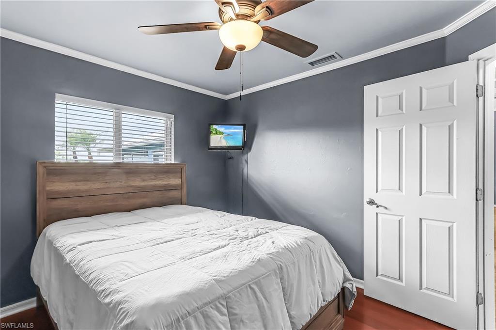 Bedroom featuring crown molding, dark wood-type flooring, and ceiling fan