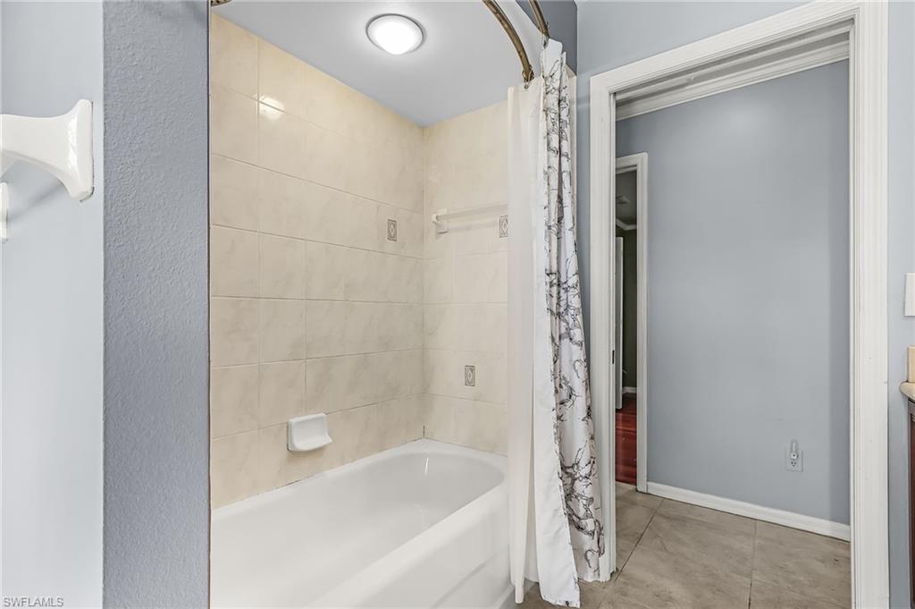 Full bathroom with shower / bathtub combination with curtain and baseboards