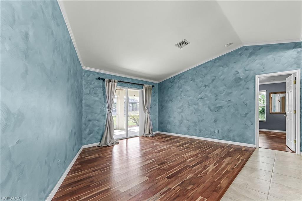 Empty room with crown molding, wood finished floors, and vaulted ceiling