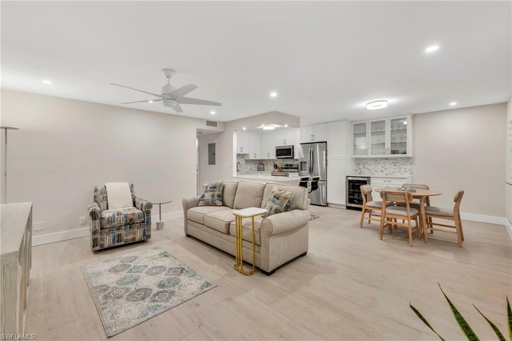 Living room featuring beverage cooler, light wood-style flooring, ceiling fan, and recessed lighting
