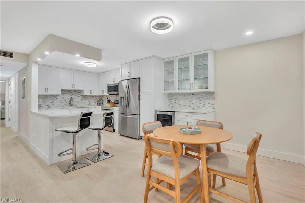 Kitchen featuring white cabinets, stainless steel appliances, a peninsula, recessed lighting, and a kitchen bar