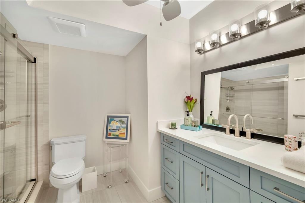 Bathroom featuring vanity, a stall shower, and a ceiling fan