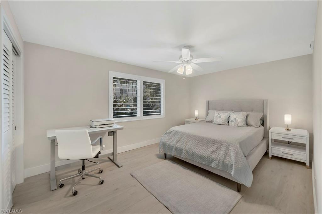 Bedroom featuring light wood-style flooring, a ceiling fan, a closet, and an office area