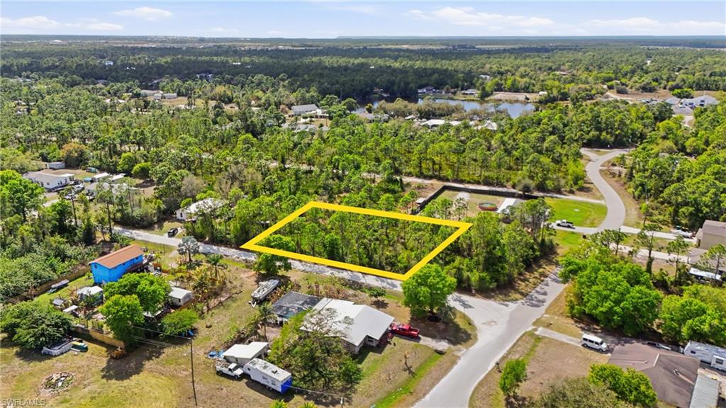 Aerial view of residential area featuring property boundaries highlighted and a heavily wooded area