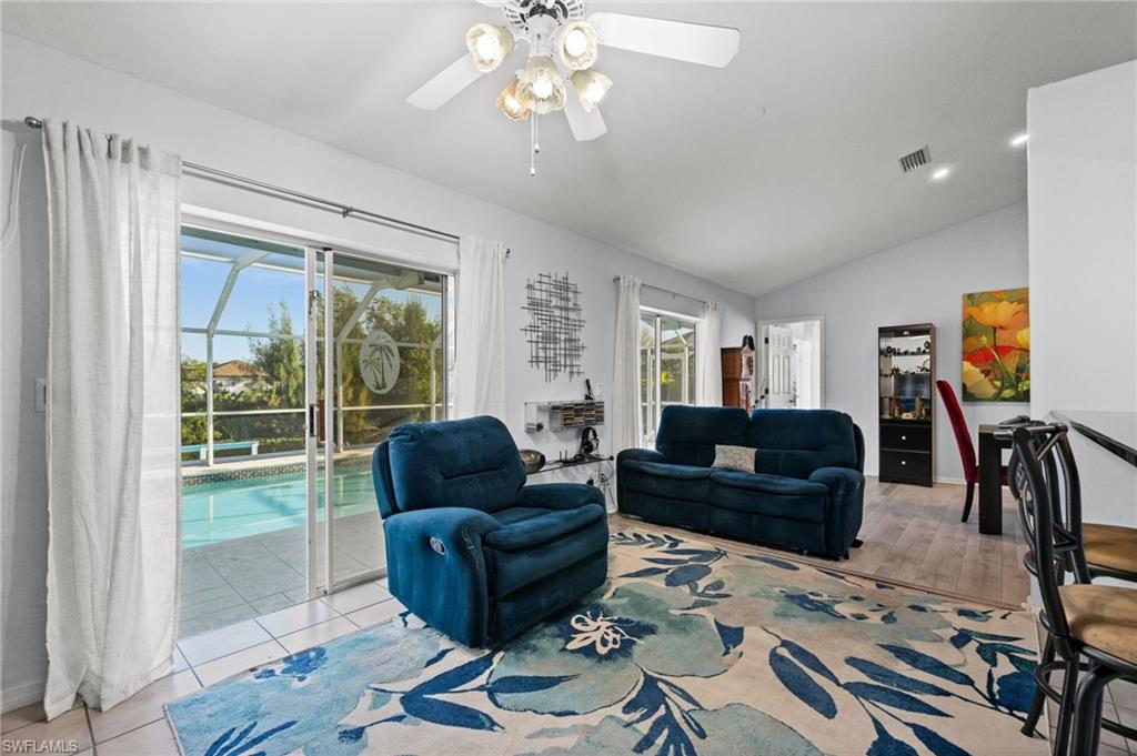 Living area featuring ceiling fan, lofted ceiling, and a view of the pool