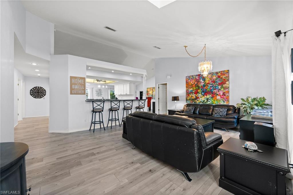 Living room featuring a chandelier, light wood-style floors, and vaulted ceiling