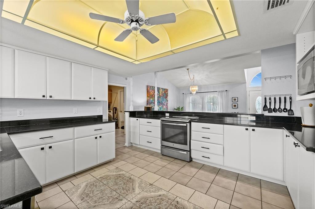 Kitchen featuring stainless steel appliances, white cabinetry, and dark stone counters