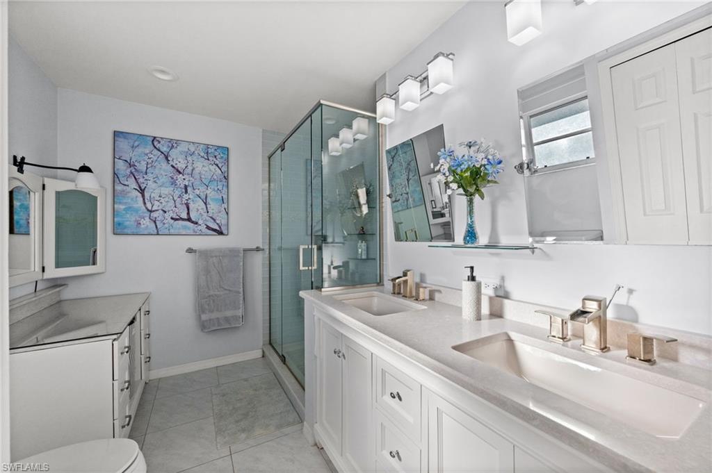 Full bath featuring double vanity, a shower stall, and light tile patterned floors
