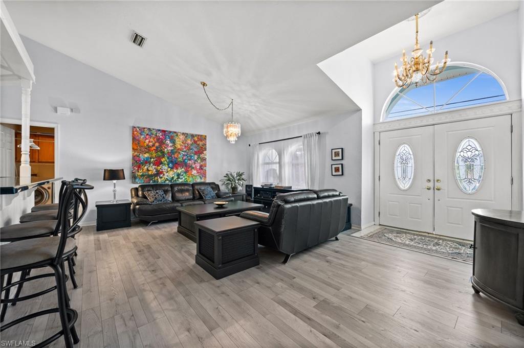 Entrance foyer with hanging lights, lofted ceiling, and light wood-style floors