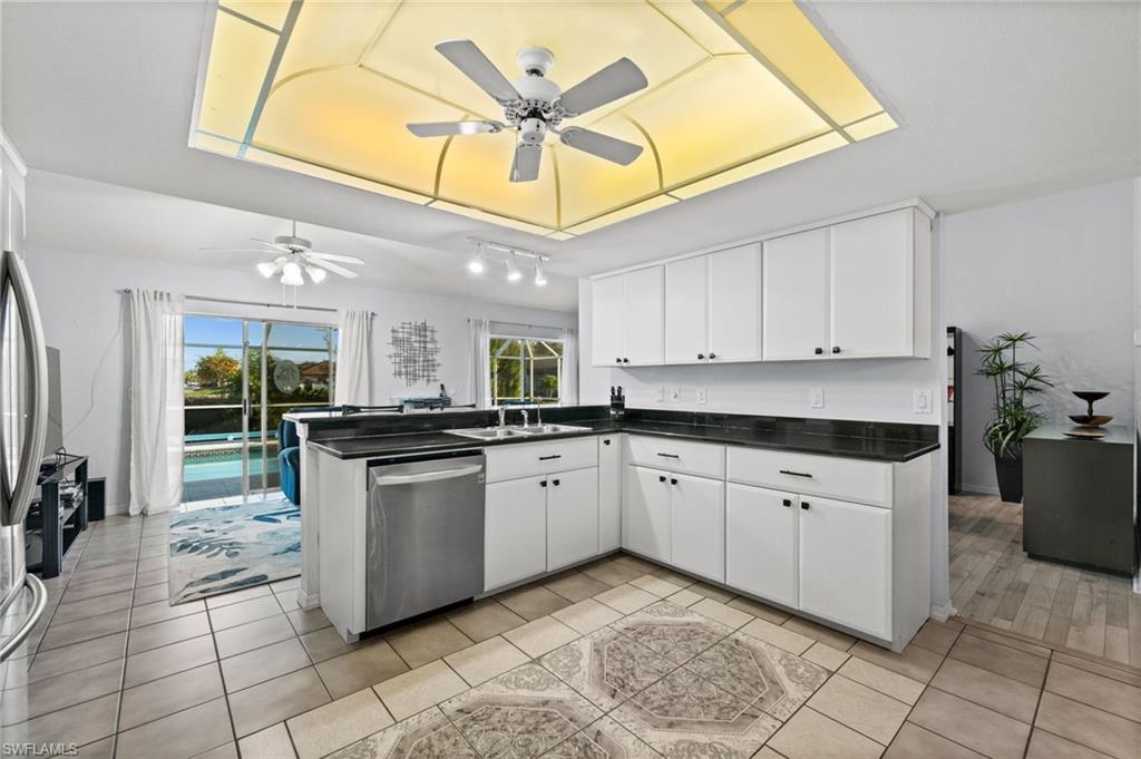 Kitchen with dark countertops, stainless steel appliances, white cabinets, a ceiling fan, and rail lighting