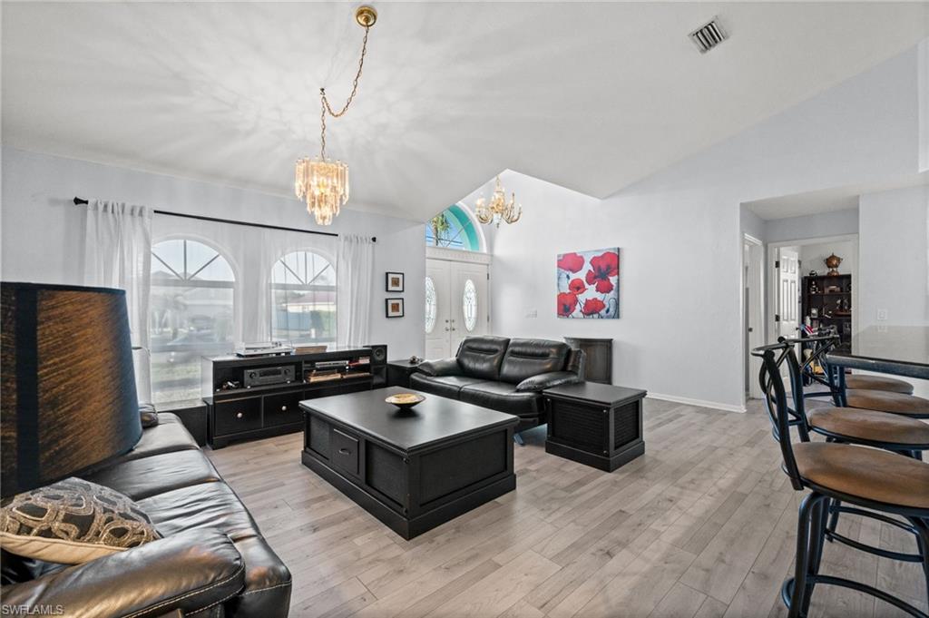 Living area featuring lofted ceiling, light wood-style flooring, and suspended lighting