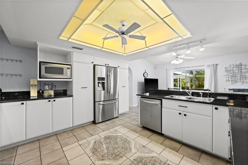 Kitchen with white cabinets, stainless steel appliances, arched walkways, track lighting, and ceiling fan
