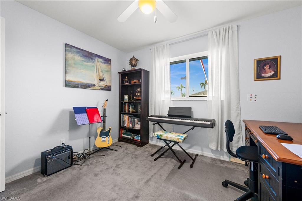 Home office with light colored carpet and ceiling fan