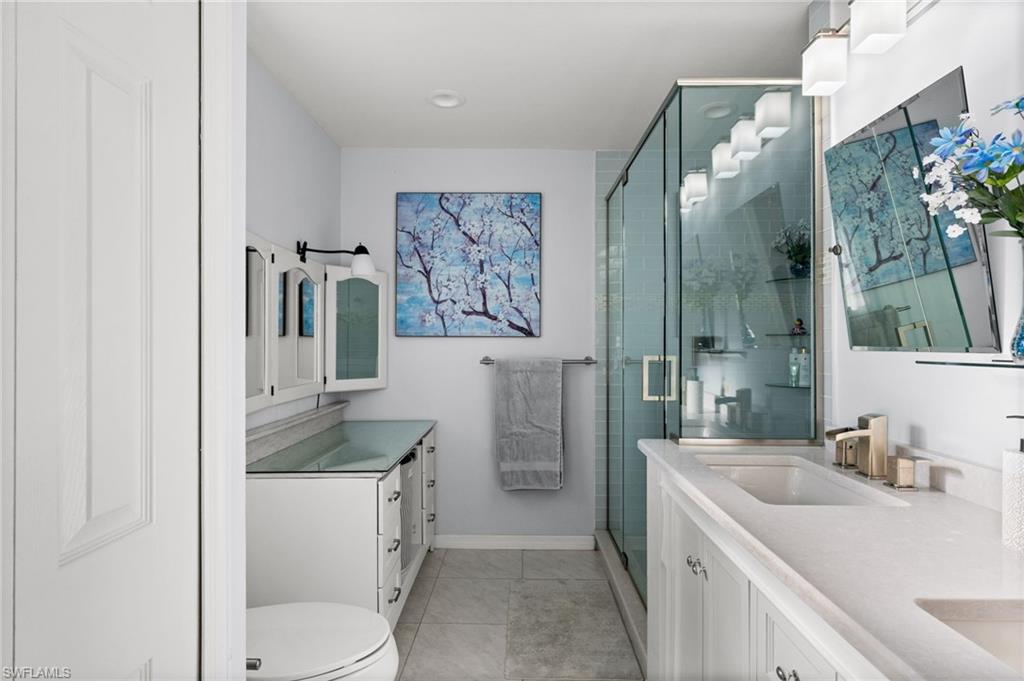 Bathroom featuring double vanity, a stall shower, and light tile patterned floors