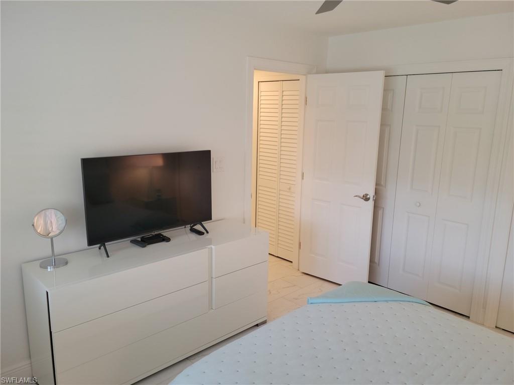 Guest Bedroom with tile floors, lighted ceiling fan, flat screen TV